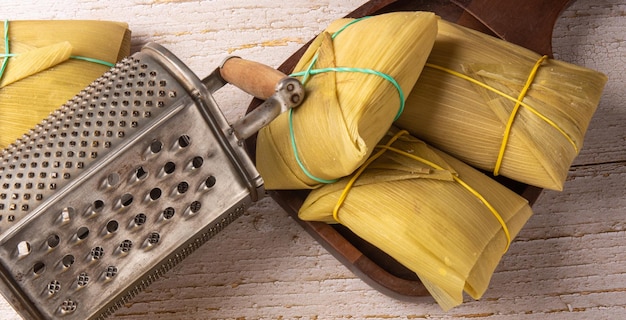 Pamonha comida brasileña a base de maíz dispuesta en una mesa de madera rústica vista superior