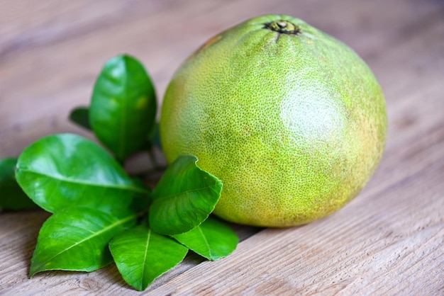 Pampelmusenfrucht auf hölzernem Hintergrund frische grüne Pampelmuse und grünes Blatt frome Pampelmusenbaumpummelo-Grapefruit im Sommer tropische Frucht in Thailand