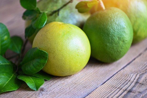 Pampelmusenfrucht auf Holzhintergrund Frische grüne Pampelmuse und Blätter von Pampelmusenbaum pummelo Grapefruit im Sommer tropische Früchte in Thailand