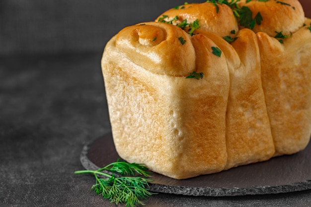 Pan con ajo y perejil verde en placa de piedra de pizarra redonda enfoque selectivo de fondo oscuro