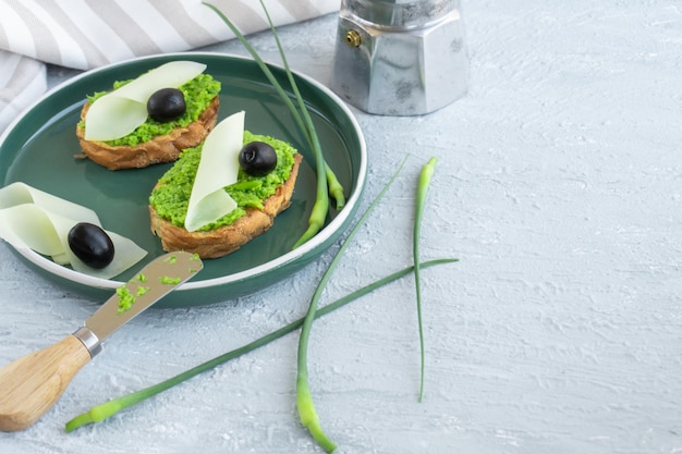 Pan de ajo. Rebanadas de baguette con mantequilla de ajo, aceitunas, queso y flechas de ajo en placa verde