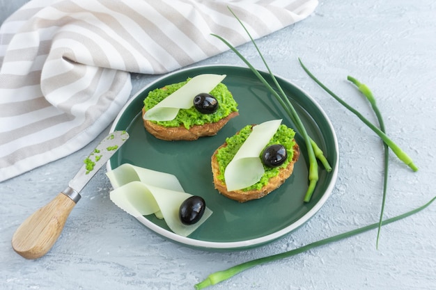 Pan de ajo. Rebanadas de baguette con mantequilla de ajo, aceitunas, queso y flechas de ajo en placa verde