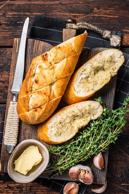 Pan de ajo tostado con hierbas y mantequilla sobre tabla de cortar de madera Fondo de madera Vista superior