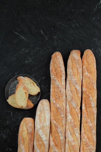 Pan baguette francés sobre mesa de mármol negro, vista superior con espacio para copiar texto