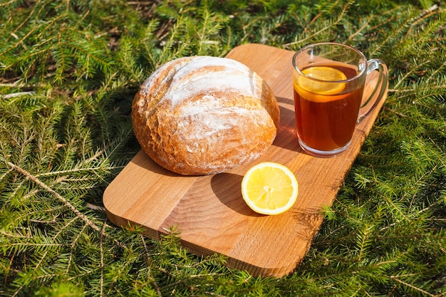 Pan blanco fresco en una tabla para cortar y té rojo con limón