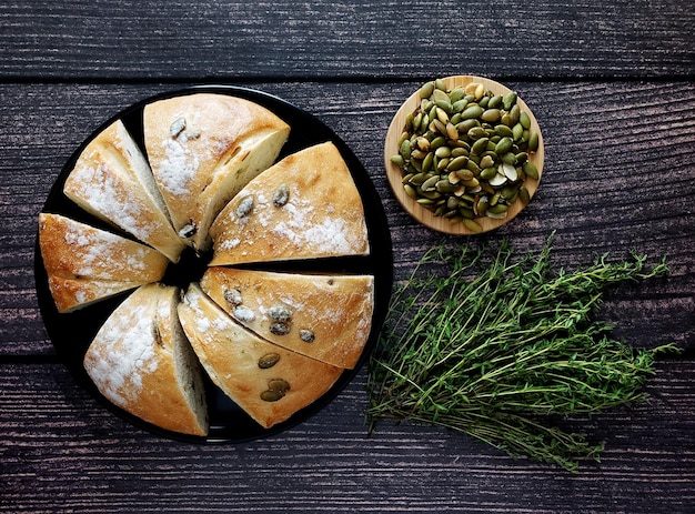 Pan de calabaza con semillas de calabaza y tomillo sobre fondo de madera, vista superior