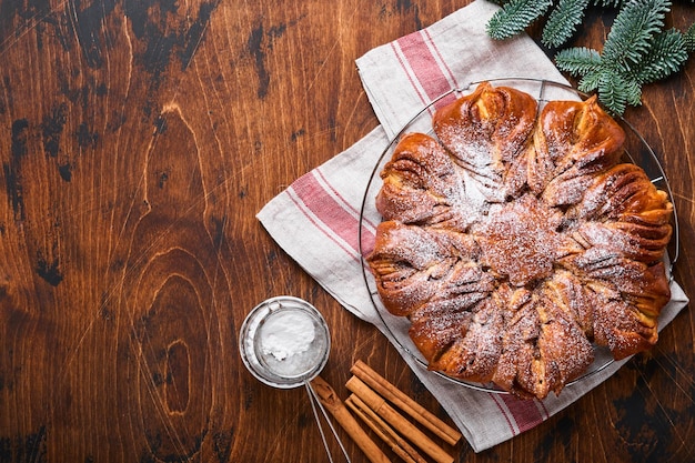 Pan de canela navideño hornear pan de canela y chocolate trenzado estrella de Navidad en una vieja mesa de madera marrón Copiar espacio para texto Vista superior