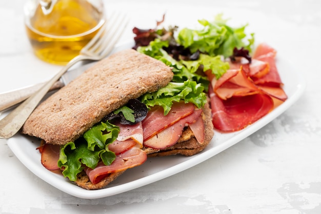 Pan con carne ahumada y ensalada en plato