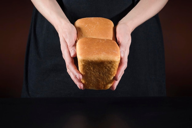 Pan casero en manos femeninas de un chef sobre un fondo oscuro