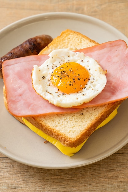 Pan casero con queso tostado, jamón y huevo frito con salchicha de cerdo para el desayuno.