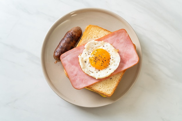 Pan casero con queso tostado, jamón y huevo frito con salchicha de cerdo para el desayuno.