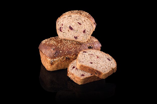 Pan casero recién horneado aislado en negro, cortado en medio pan de centeno con frutos rojos