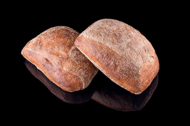 Pan casero recién horneado aislado en negro. Pan ciabatta italiano. Alimentación saludable y panadería tradicional, concepto de pan para hornear.