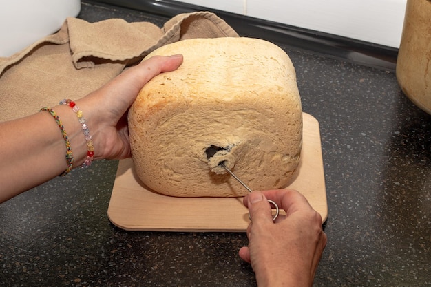 pan casero recién horneado de una máquina de pan El ama de casa saca un cuchillo del pan para amasar la masa