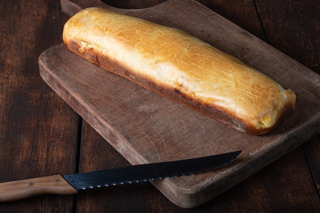 Pan casero relleno de pollo desmenuzado en madera rústica y cuchillo