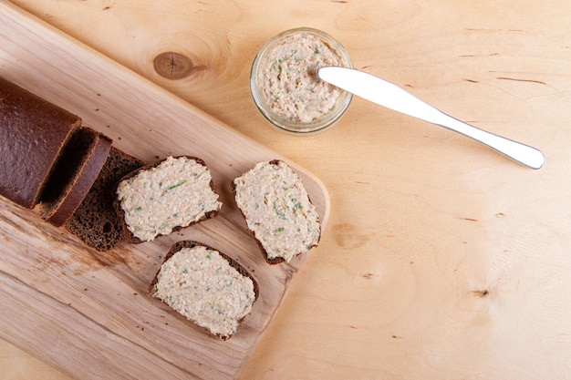 Foto pan casero en una tabla de cortar de madera con paté y cebollas de primavera