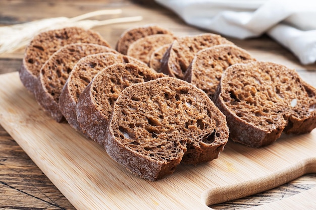 Pan de centeno con cereales, una hogaza de baguette de grano fresco sobre un fondo de madera.