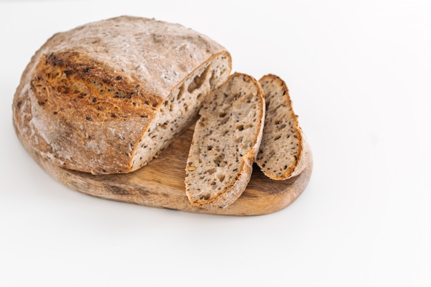 Pan de centeno de grano entero orgánico recién horneado en tabla de cortar de madera