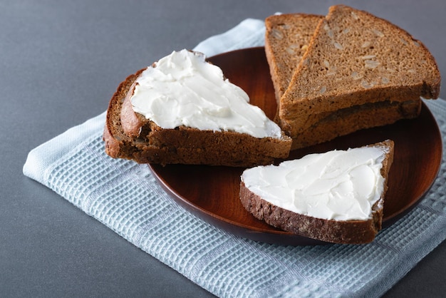 Pan de centeno con queso crema en plato de madera comida rústica