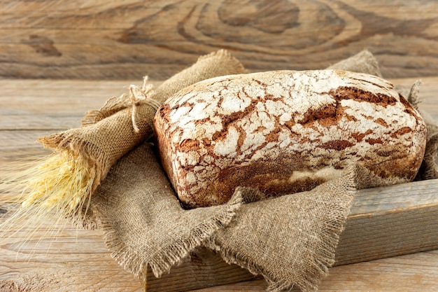 Pan de centeno recién horneado sobre arpillera sobre fondo rústico. Alimentos orgánicos caseros.