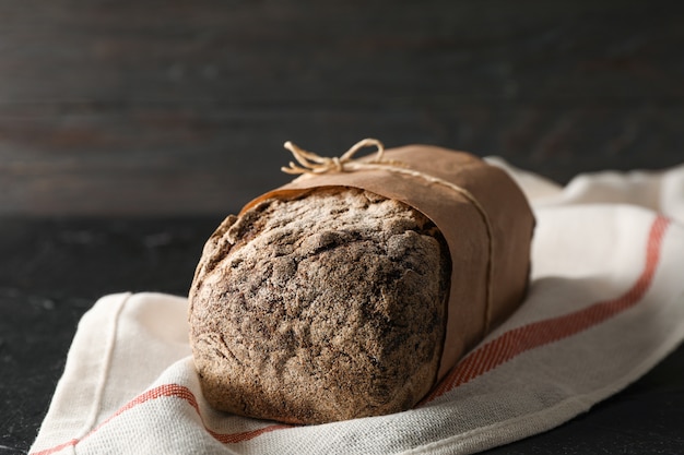 Pan de centeno en la toalla de cocina en la mesa negra contra el espacio de madera, espacio para texto y primer plano