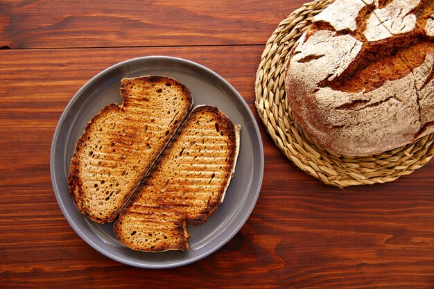 Pan de centeno tostadas rebanadas sobre madera oscura.