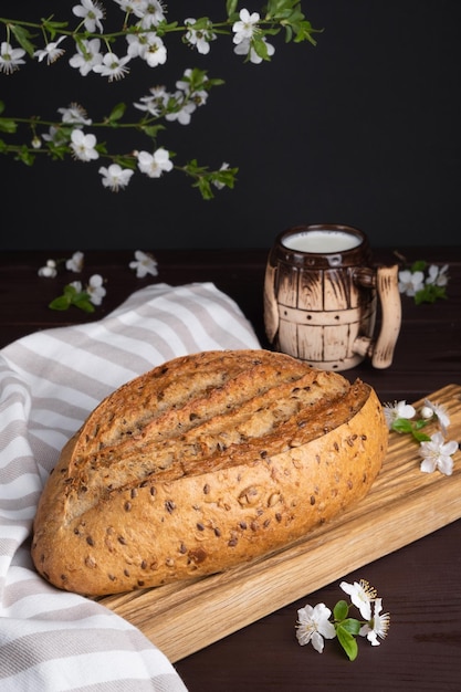 Pan de cereal de centeno casero fresco con taza de arcilla de leche en tabla de cortar de madera Desayuno saludable