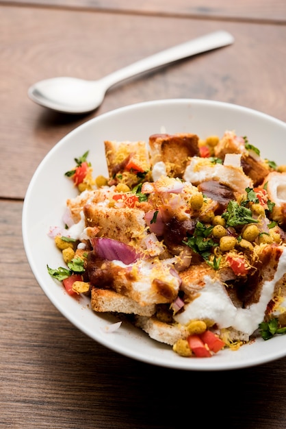 El pan chaat, chat es un delicioso entrante o aperitivo de la India, que se sirve en un tazón adornado con tomate, sev, cilantro y masala. enfoque selectivo