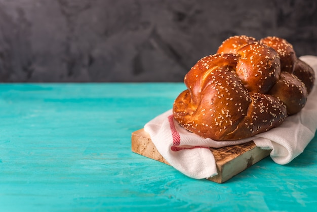 Foto pan challah en una placa de madera en mesa de madera