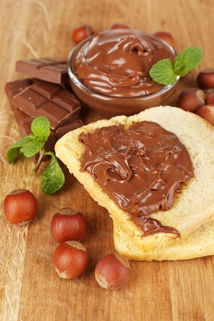 Pan con chocolate dulce y avellanas para untar sobre fondo de madera