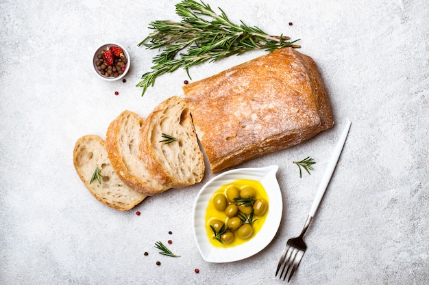 Pan ciabatta italiano cortado en rodajas con hierbas y aceitunas.