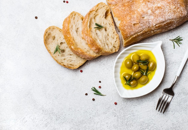 Pan ciabatta italiano cortado en rodajas con hierbas y aceitunas