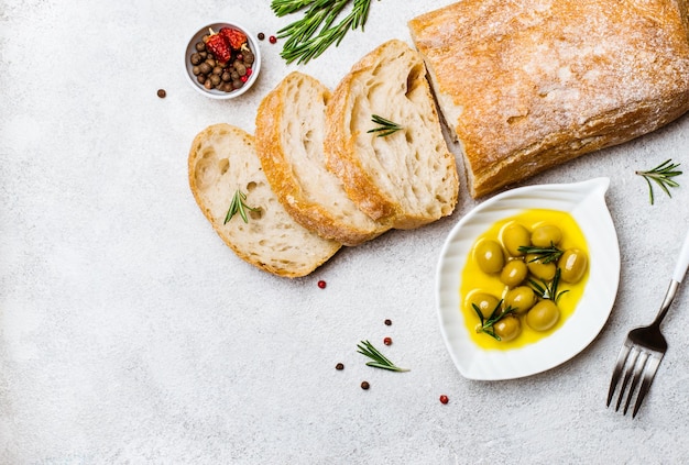 Pan ciabatta italiano cortado en rodajas con hierbas y aceitunas