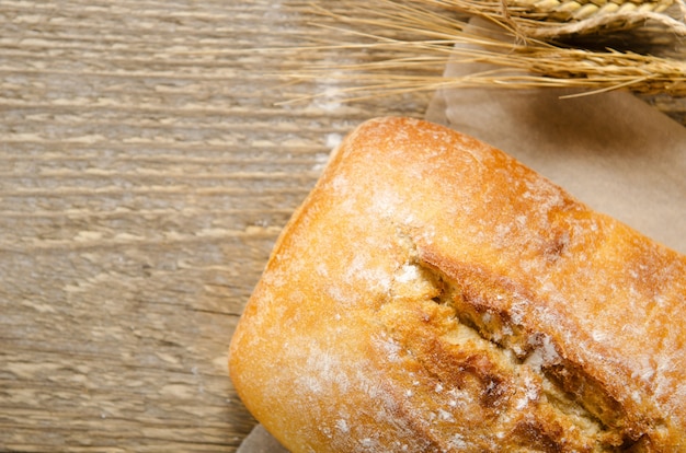 Pan ciabatta en una mesa de madera sobre papel de hornear. Estilo rústico, italiano.