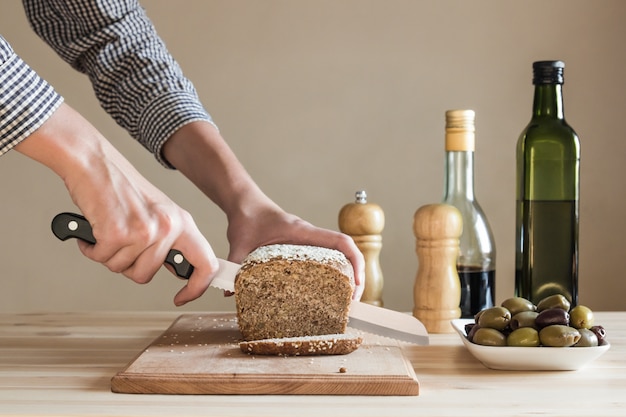 Pan cortado por manos femeninas en la cocina