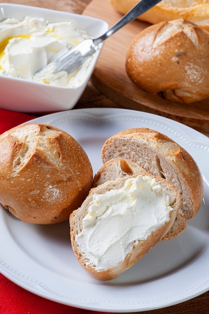 Pan con cuajada. Plato blanco y mesa de madera.