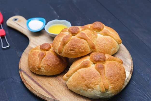 Pan de muerto na placa de madeira em fundo escuro. Copie o espaço. Dia dos Mortos. Feriado mexicano. Comida mexicana.