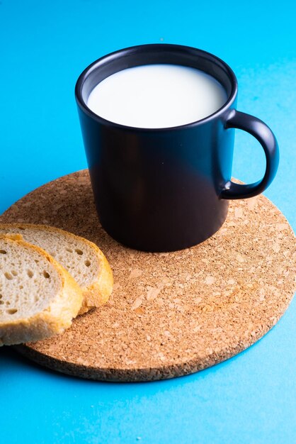 Pan de desayuno y una taza de leche sobre fondo amarillo y azul.