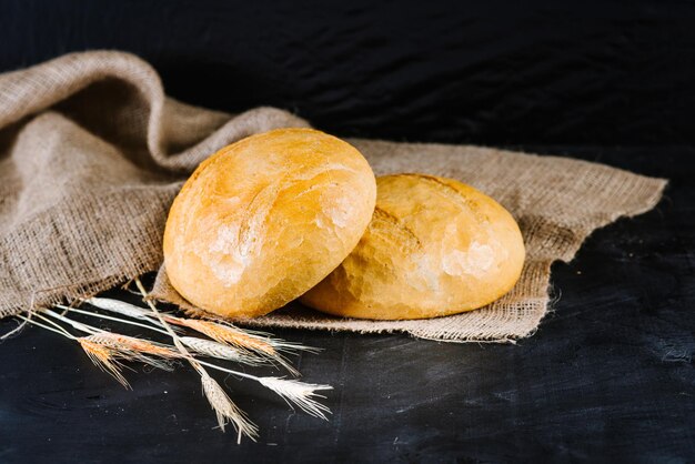 Pan dulce y sabroso y trigo sobre fondo de madera negra