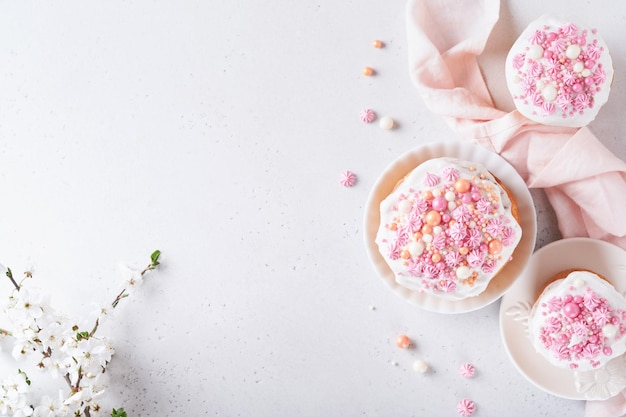 Pan dulce tradicional de Pascua o pasteles con glaseado blanco y decoración de azúcar huevos de colores y rama de cerezo sobre mesa blanca Varios pasteles de Pascua de primavera Feliz día de Pascua Enfoque selectivo