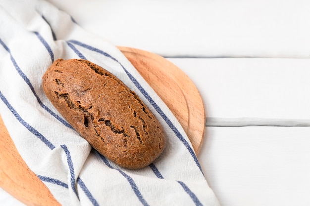 Pan de einkorn de masa madre oscura sobre mesa de madera blanca con espacio para texto