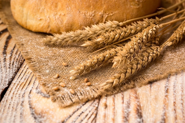 Pan con espigas de harina de trigo y granos en mesa de madera Concepto de agricultura y cosecha