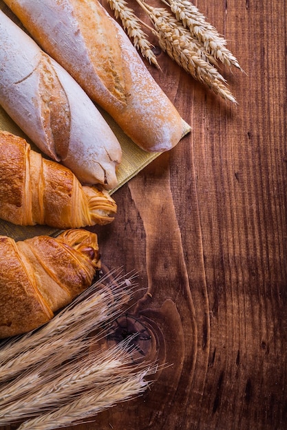 Pan y espigas de trigo en concepto de comida y bebida de tablero de madera vintage