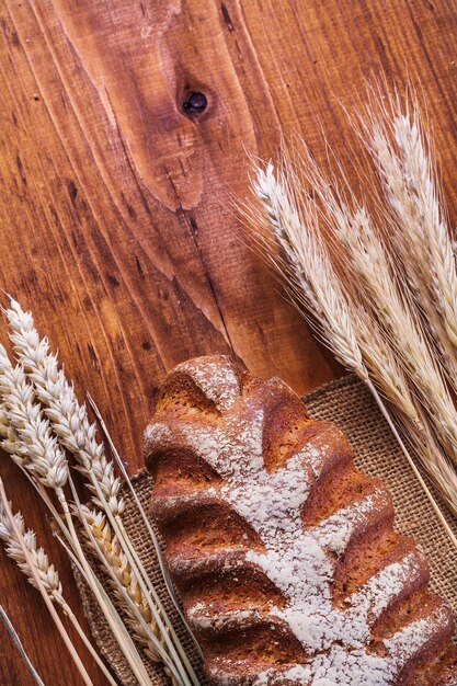 Pan y espigas de trigo en concepto de comida y bebida de tablero de madera vintage