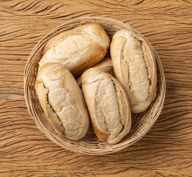 Pan francés de grano entero, pan de sal o pistolet en una cesta sobre una mesa de madera