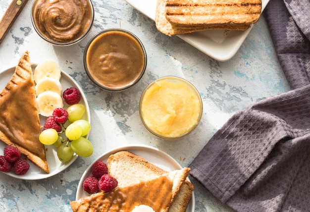 Pan francés con mantequilla de almendras y frutas. pan tostado con mantequilla de nuez. pan tostado casero con mermelada y mantequilla de maní en la mesa de madera para el desayuno.