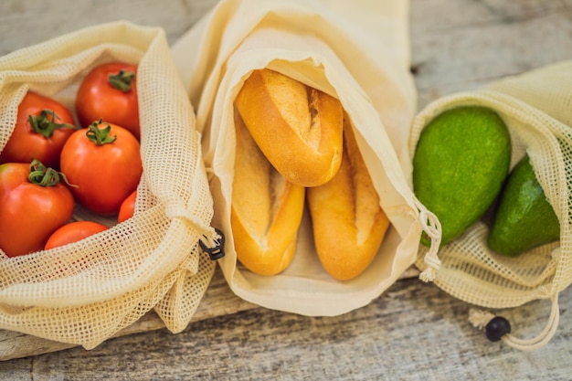 Foto pan fresco, aguacate y tomates en una bolsa reutilizable en una elegante superficie de cocina de madera sin desperdicio