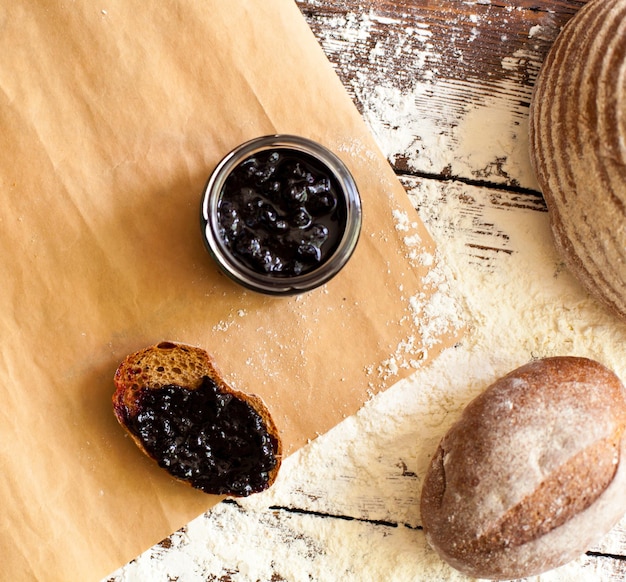 el pan fresco está sobre la mesa de madera espolvoreado con harina y una rebanada de pan con deliciosas bayas