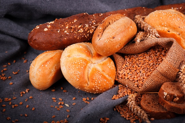 Pan fresco fragante sobre la mesa. Concepto de comida. Panadería, crujientes hogazas de pan y bollos. Surtido de pan horneado