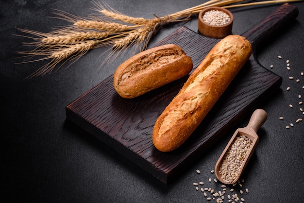 Pan fresco sobre fondo negro, vista superior, espacio de copia. Varias hogazas de pan de trigo y centeno caseras recién horneadas